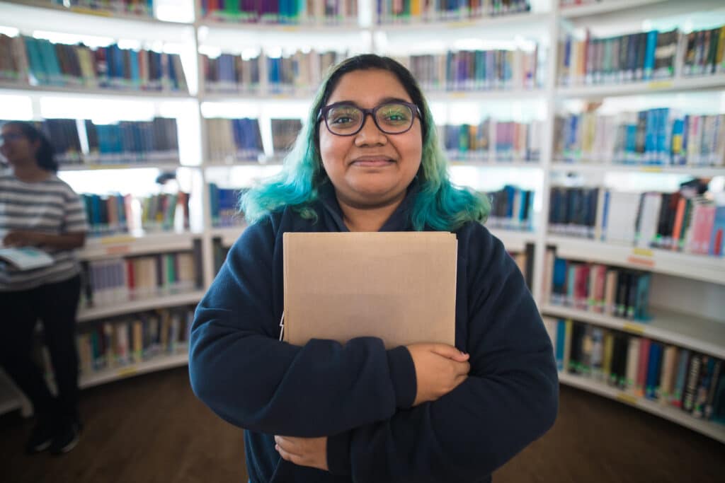 Portrait of student holding book in a library